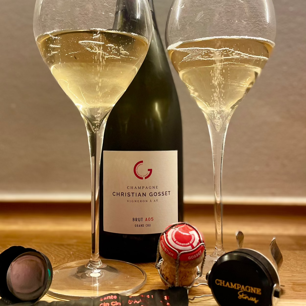 Close up af Champagne Christian Gosset A05 Brut Grand Cru med 2 fyldte champagne glas, prop og stopper. Bobler i glassene
