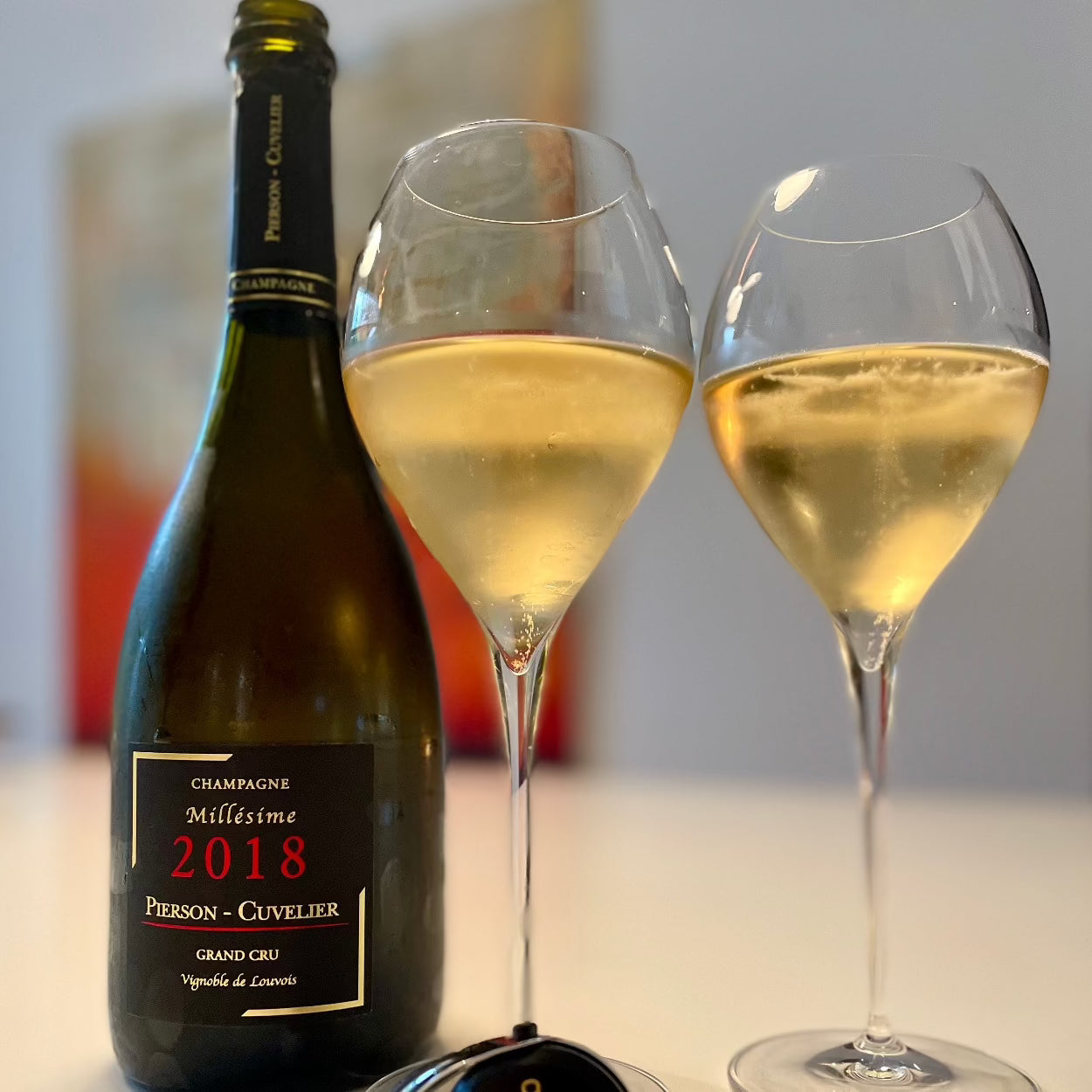 1 flaske årgangschampagne fra Champagne Pierson-Cuvelier, Millésime 2018, Grand Cru,  2 Lehmann Grand Jamesse champagneglas med champagne ved siden af, uskarp baggrund