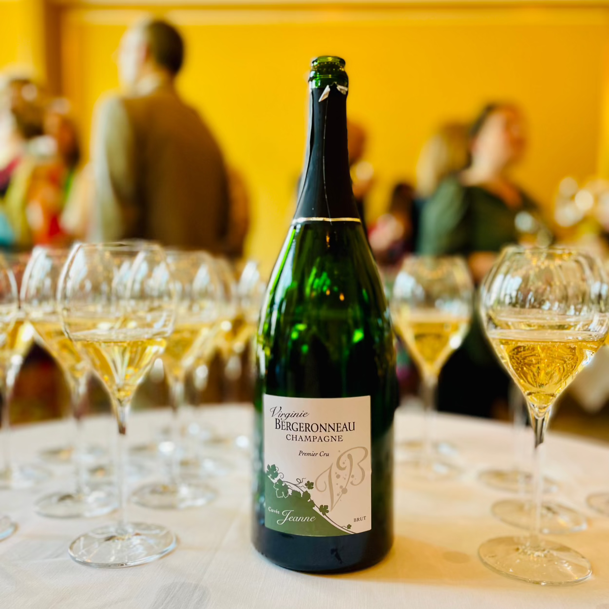 Champagne Virginie Bergeronneau Cuvée Jeanne og mange champagneglas med champagne, mennesker uskarpt i baggrunden